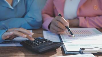 Two business people are working on paperwork and a calculator video