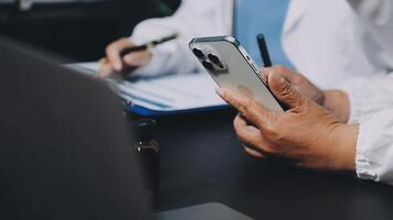 A doctor is using a smartphone while sitting at a desk video