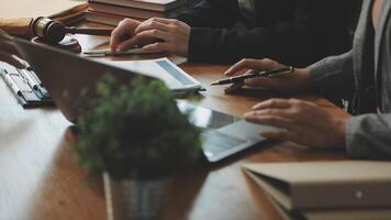 A group of people sitting at a table with laptops and papers video