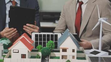 Two men in suits are looking at a model of a house with wind turbines video