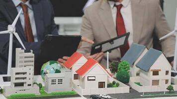 Two men in suits are looking at a model of a house video