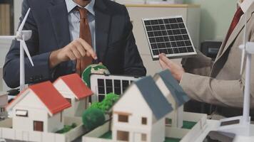 Two men in suits are looking at a model of a house with solar panels video