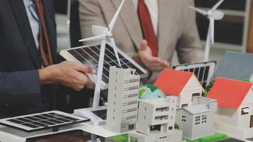 Two men in suits are looking at a model of a house with wind turbines video