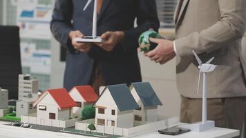Two men in suits are looking at model houses video