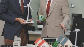 Two men in suits holding a model of a house with wind turbines video