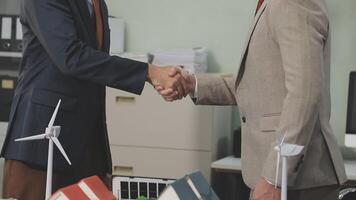 Two businessmen shaking hands in front of a desk video