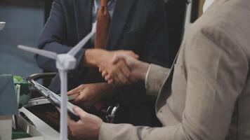 Two business men shaking hands in front of a wind turbine video