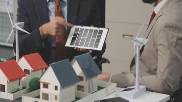 Two men in suits are looking at a model of a house with solar panels video