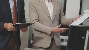 Two men in suits standing in front of a computer video