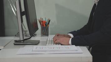 A man in a suit is typing on a computer video