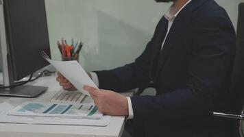 A man in a suit is sitting at a desk with a piece of paper video
