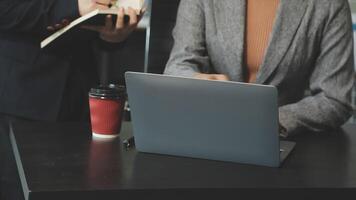 A man and woman sitting at a table with a laptop video