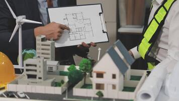 A man and woman are looking at a model of a house video