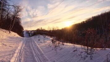 A snowy road with a sun setting behind it video