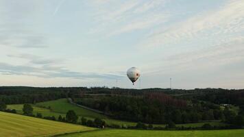 Drone shot, view of a hot air balloon in the sky flying over green fields and forests on a bright summer day, Germany. video
