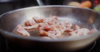 Bacon is fried in a frying pan, tongs stir it, there are no people video