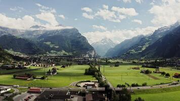 A low-rise town with picturesque traffic, located in a lowland at the foot of the Alps. Panoramic shooting from a drone, Switzerland video