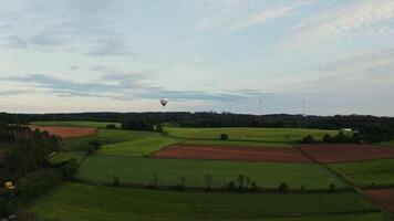 Drone shot, view of a hot air balloon in the sky flying over green fields on a sunny day, Germany. video