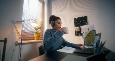 A man and a woman in informal clothes work sitting at a desk in the office, using laptops and and drinking coffee with a serious look video