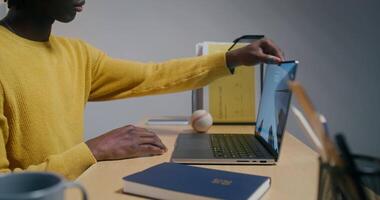 A man with glasses opens a laptop and starts typing sitting at his desk in the office, part of his face in the frame video