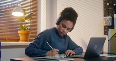 uma mulher é digitando em uma computador portátil e escrevendo dentro uma caderno sentado às dela mesa, trabalhando dentro a escritório video
