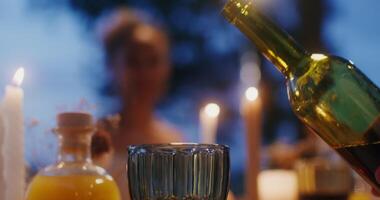 A man pours wine into a glass sitting at a beautifully served festive table, close-up of hand, no face video