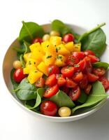 Vegetable salad with mango, cherry tomatoes and spinach in a bowl photo