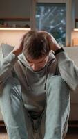 Middle-aged man sits alone at home, looking away with thoughtful expression. Concept of introspection, deep thoughts and emotional reflection video
