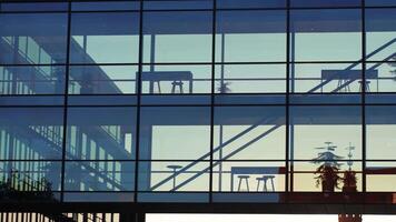 Silhouette of modern glass office building with glass sky bridge at sunset. Contemporary architecture with transparent facade and minimalist design video