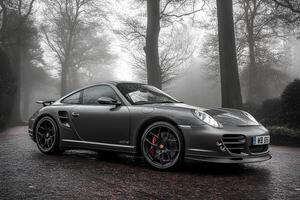 A sleek Porsche 911 Turbo S parked in a mysterious foggy forest, blending luxury with natures fog, creating a dramatic and captivating scene photo