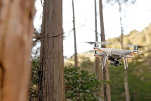 A drone equipped with a digital camera soaring over a lush forest, capturing breathtaking aerial views of the natural landscape. The scene highlights the powerful technology and stunning environment photo