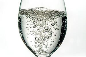 A close-up view of a glass of water with bubbles rising to the surface, isolated on a white background, highlighting the clarity and freshness of the water photo