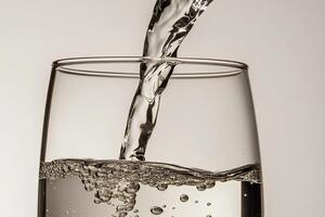 A stream of clear water being poured into a transparent glass against a white background. The crisp and refreshing composition highlights the purity and movement of water. photo