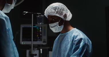 A team of surgeons in disposable caps and medical masks on their faces perform a surgical operation in the operating room. in 4k, red komodo video