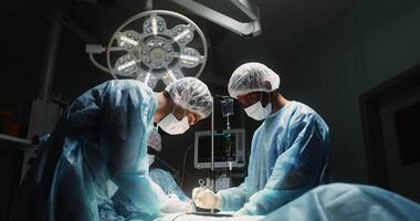 Surgical operation in a modern, well-equipped operating room. Teamwork of a surgeon, his assistant and an anesthesiologist in 4k, ed komodo video