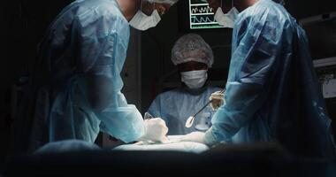A multinational team of surgeons dressed in sterile clothing performs a surgical operation in a modern, well-equipped operating room. in 4k, red komodo video