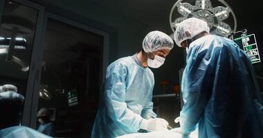 A medical team during a surgical operation under the bright light of a lamp in a well-equipped operating room. Carrying out laparoscopy in a modern medical center. in 4k, red komodo video
