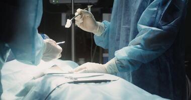 A team of surgeons perform the surgical operation in a modern, well-equipped operating room. Close-up, motion from doctors' hands to their focused faces. in 4k, red komodo video