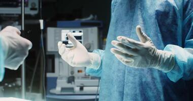 An African-American surgeon dressed in a medical gown and sterile gloves, with a disposable mask and cap on his head, is ready for surgery, motion from hand to face. in 4k, red komodo video