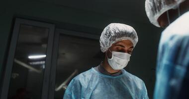 Close-up of a surgeon's face bent over a patient during surgery. Teamwork of medical personnel for surgical intervention in a modern operating room. in 4k, red komodo video