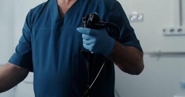 A gastroenterologist performs diagnostics of the patient's colon using the microcamera control joystick. The patient is not visible, doctor close-up. 4k , red komodo video