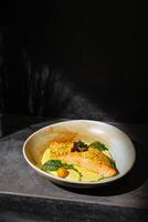 Delicious salmon fillet served on smooth culinary cream with fresh garnishes in an elegant setting photo