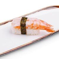 Sushi made with shrimp and rice on a rectangular white plate in a minimalistic setting photo