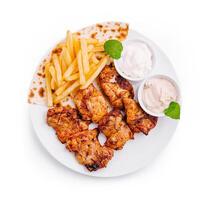 Grilled chicken with fries and sauces served on a white plate at a restaurant photo