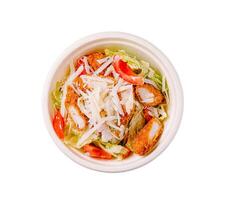 Fresh salad with crispy chicken, lettuce, tomatoes, and cheese prepared in a takeout bowl for a quick meal option photo