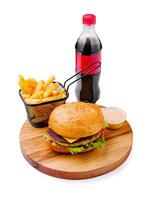 Delicious burger meal served with golden fries, refreshing soda, and savory sauce on a wooden platter photo