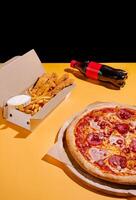 Delicious pizza, crispy chicken, and fries paired with soda create a perfect meal on a bright yellow table photo