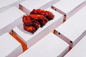 Different boxes filled with crispy chicken wings arranged creatively on an orange background photo