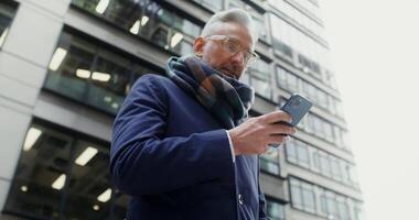 Modern mobile phone in the hands of a businessman in a business suit typing while standing on the street near the office center. in 4k, red komodo video