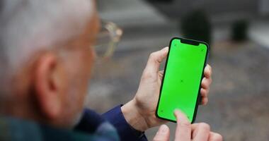 uma homem usando Móvel telefone com verde tela tremendo dele dedo através a tela para a lado, irreconhecível pessoa, topo Visão a partir de atrás a do homem ombro. croma chave, brincar. dentro 4k, vermelho Komodo video